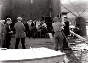 View of an outdoor set at Universal Studios in 1925, with Park Ries cranking the camera